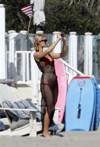 Paris Hilton at the beach in a skimpy red bikini and fishnet kaftan in Malibu.July 12, 2013