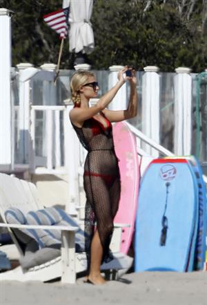 Paris Hilton at the beach in a skimpy red bikini and fishnet kaftan in Malibu.July 12, 2013