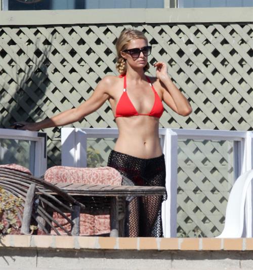 Paris Hilton at the beach in a skimpy red bikini and fishnet kaftan in Malibu.July 12, 2013