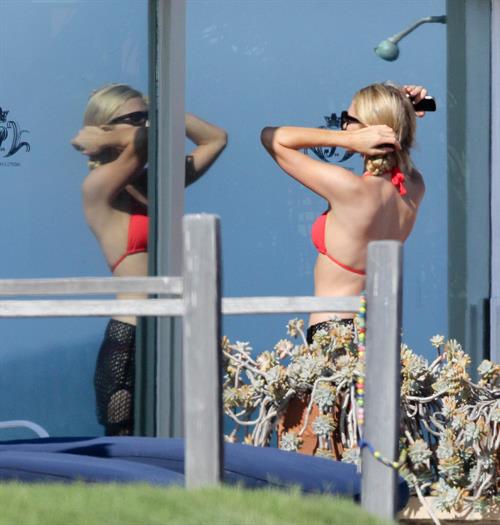 Paris Hilton at the beach in a skimpy red bikini and fishnet kaftan in Malibu.July 12, 2013