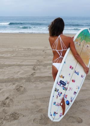Shay Mitchell at the beach with a surfboard