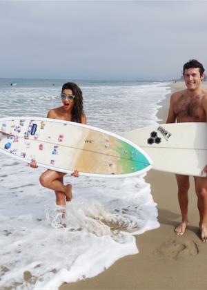 Shay Mitchell at the beach with a surfboard