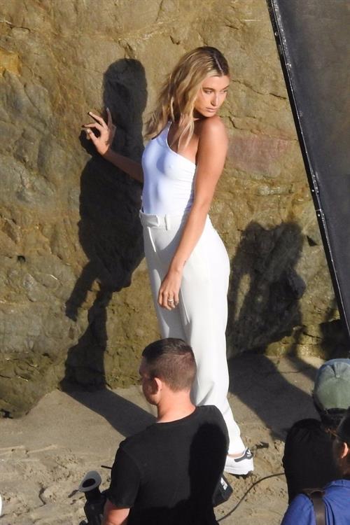 Hailey Bieber Pictures Hailey Bieber braless nipples pokies in a white top at the beach seen by paparazzi during a photo shoot.