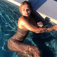 Elizabeth Hurley nude in a pool covering her topless boobs with her arm.





