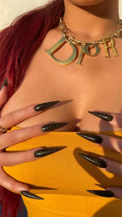 Kylie Jenner grabbing her big tits while wearing a sexy little minidress with her braless boobs showing nice cleavage.