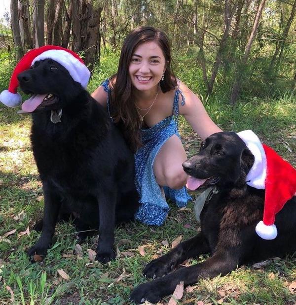 Jess Dardo wearing a low-cut dress, in a Christmas-themed photo with her pet dogs.