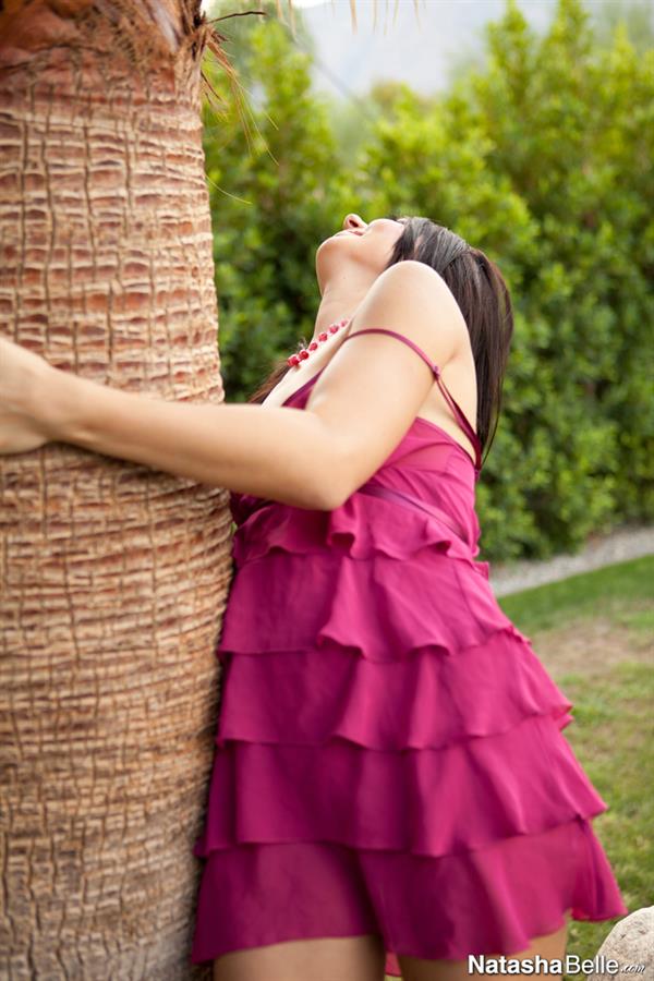 Natasha Belle poses next to a palm tree